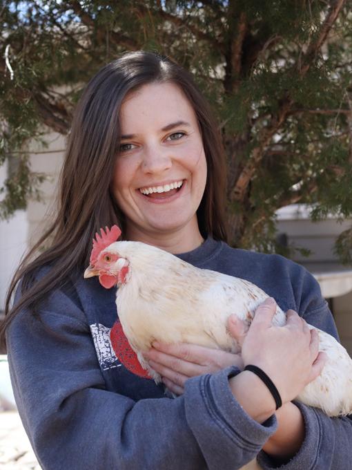 a brunette girl holding a white chicken