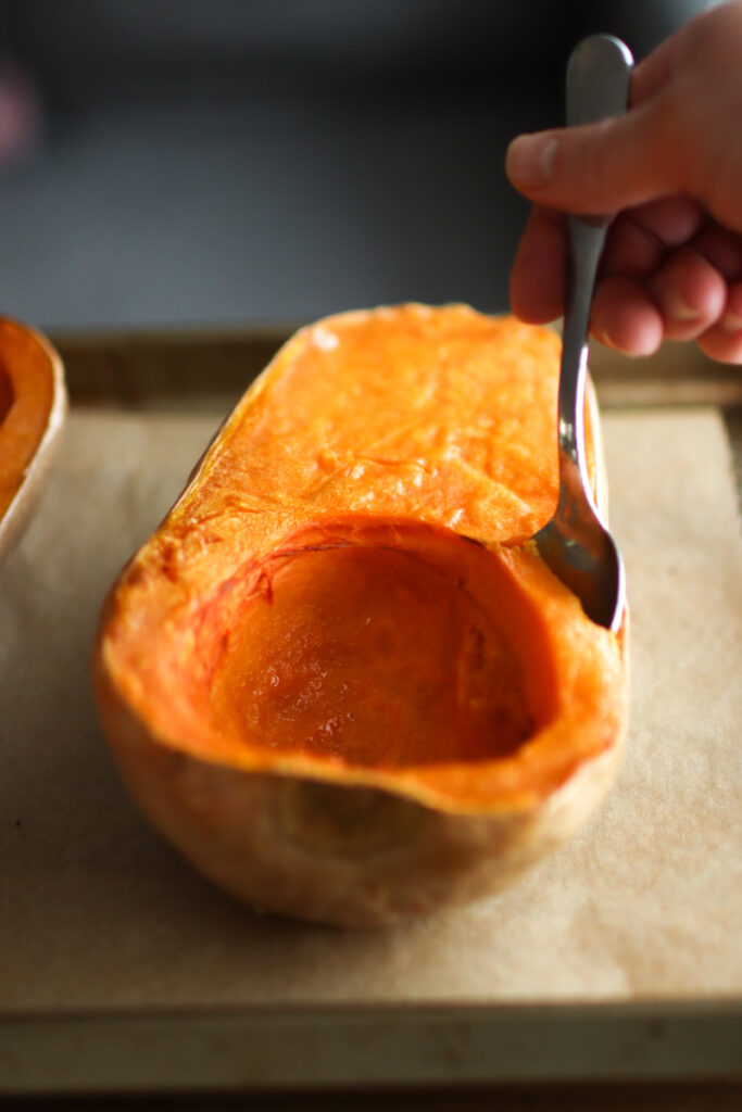 scooping butternut squash out of its skin
