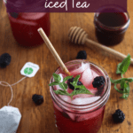 a glass of blackberry iced tea with blackberries, mint, and a tea bag
