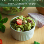 a bowl of pesto orzo pasta salad with an onion, mozzarella, and basil.