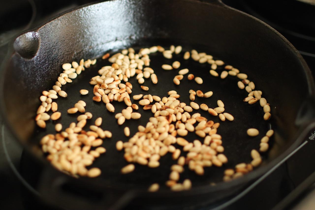 a skillet with pine nuts in it