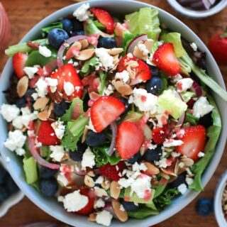 looking down at a summer berry salad with berries, almonds, and dressing around it.