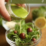 pesto salad dressing being poured onto a salad