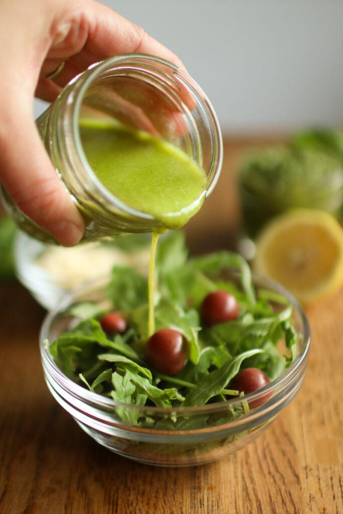 dressing being poured onto a salad