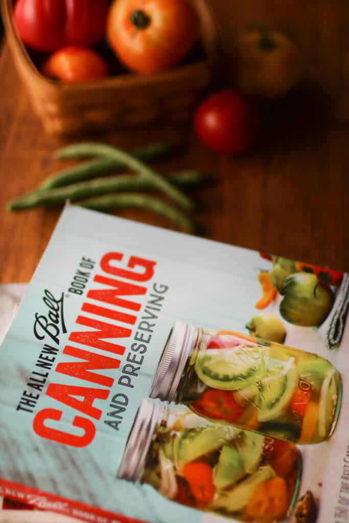 a book on canning with a basket of tomatoes and a pile of green beans