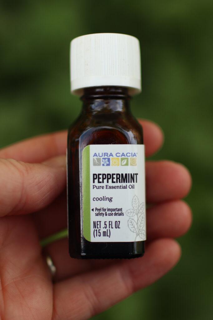 A hand holding a bottle of peppermint oil