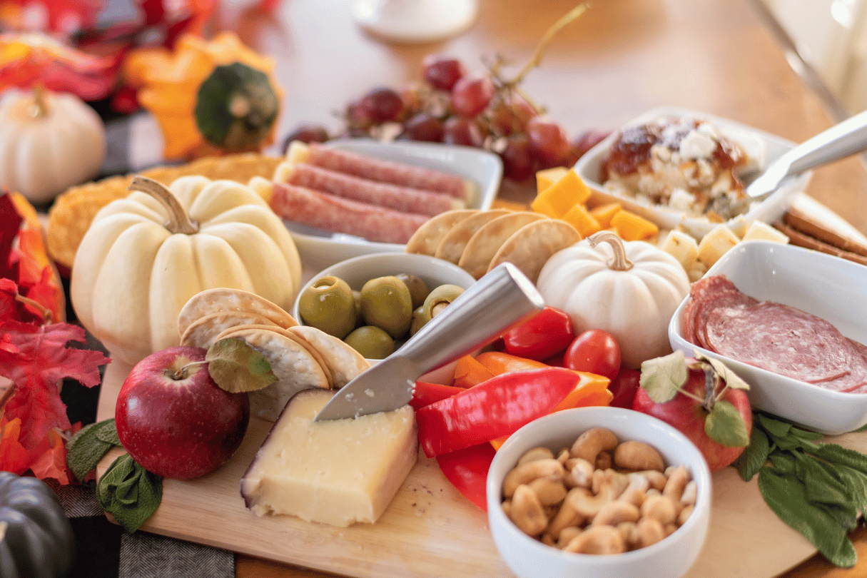 a fall charcuterie board with pumpkins and leaves
