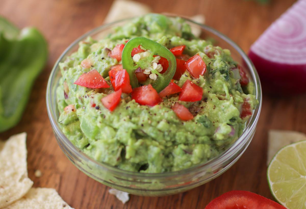 a bowl of guacamole with chips and vegetables around it