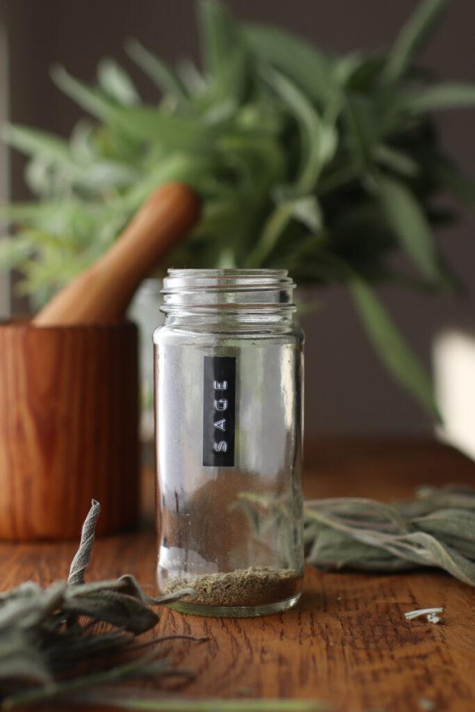 a jar of dried sage with fresh sage in the background