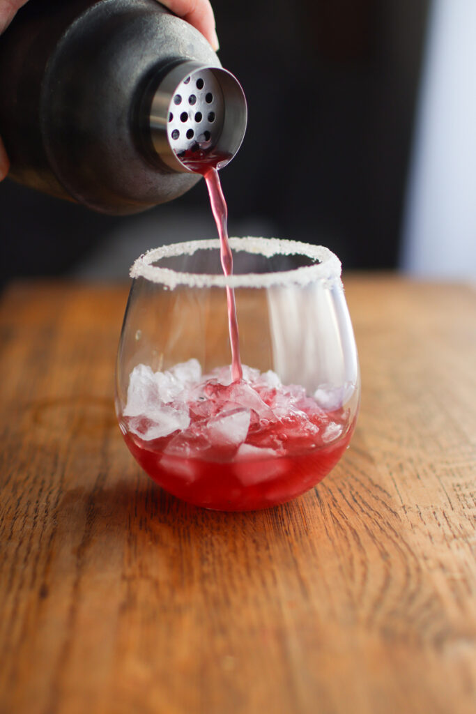 Pouring cranberry tequila cocktail from a cocktail shaker
