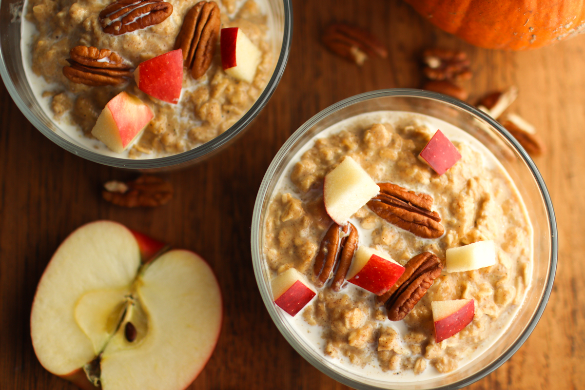 looking down on two bowls of pumpkin oatmeal and an apple half