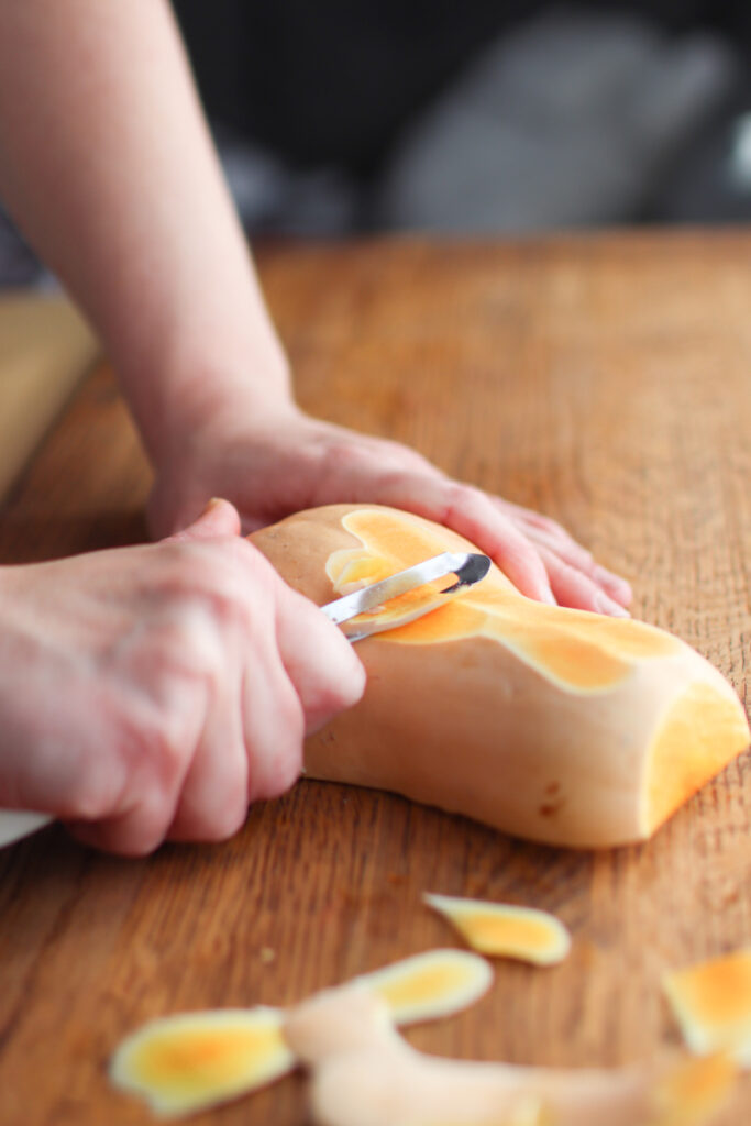 Peeling a butternut squash with a vegetable peeler