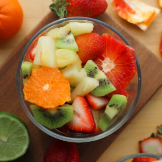 looking down on a bowl of spring fruit salad with fruit surrounding it