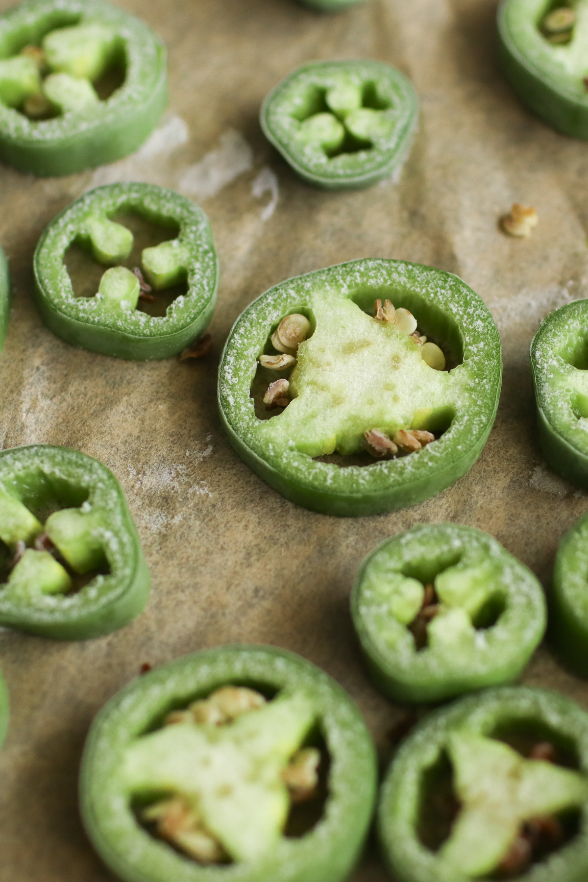 Frozen jalapeno slices on a piece of parchment paper.