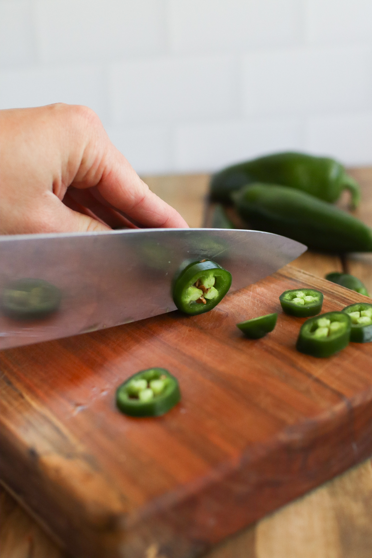 Slicing jalapenos on a wooden cutting board.