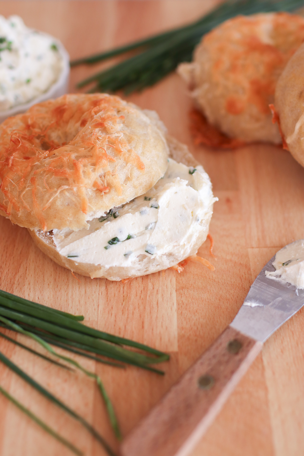 A bagel smeared with chive and onion cream cheese.