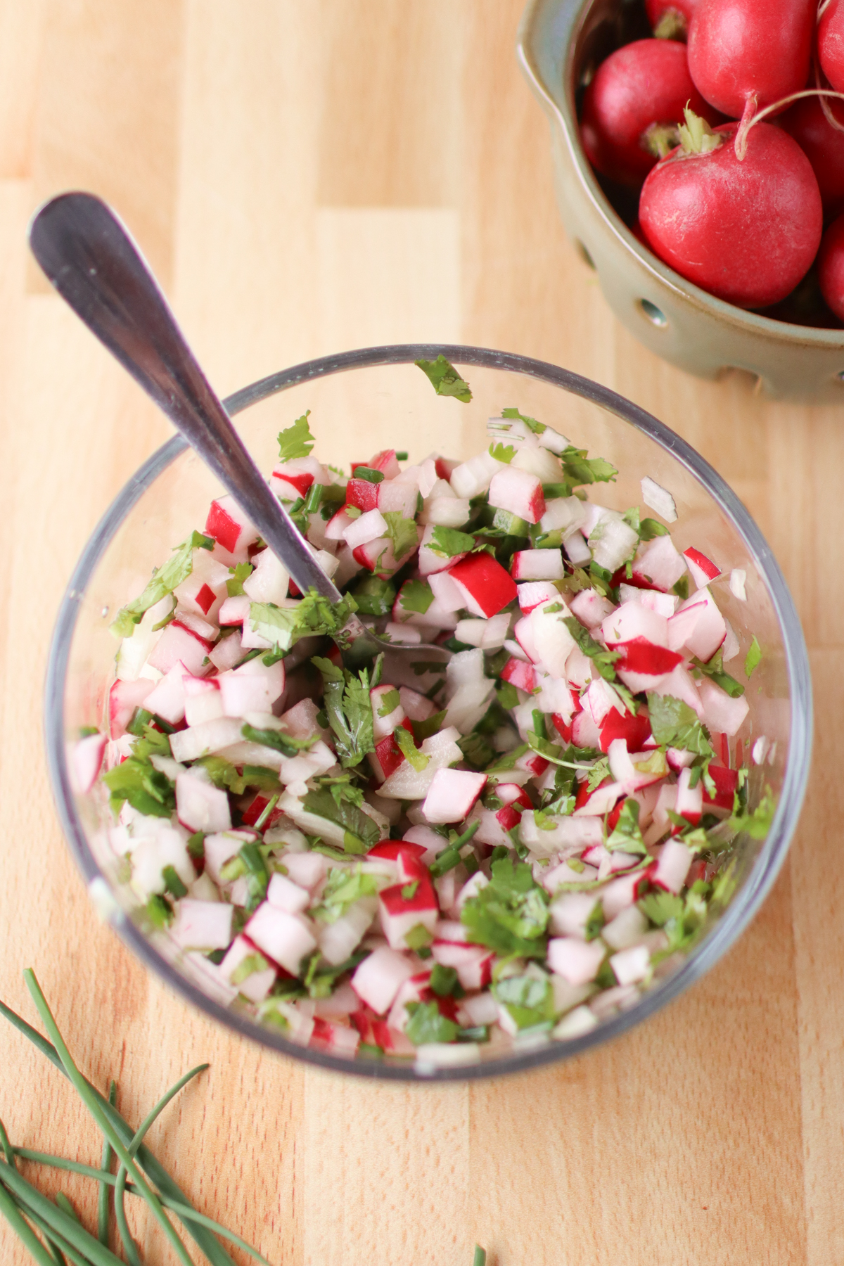Radish salsa stirred with a spoon sticking out of it.