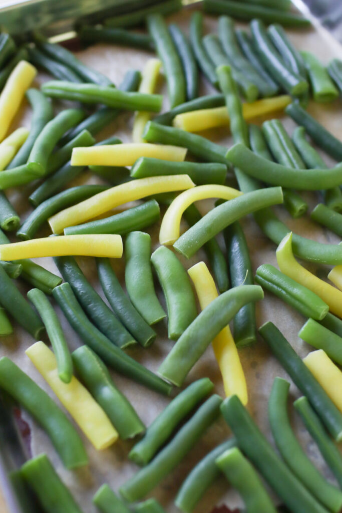 Blanched green beans on a parchment paper-lined sheet pan.