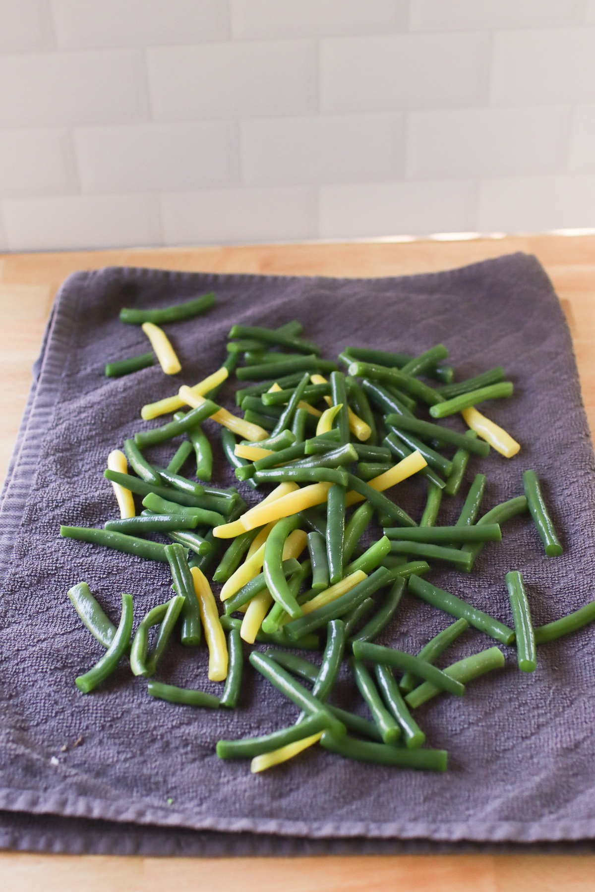 Blanched green beans drying on a kitchen towel.