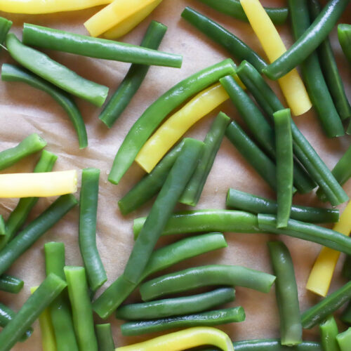 Blanched green beans on a parchment paper-lined baking sheet.