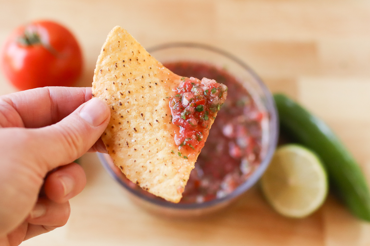 Holding a tortilla chip with blender salsa on it.